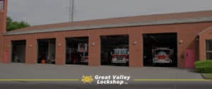 A brick fire station with open overhead doors and fire trucks sitting inside.