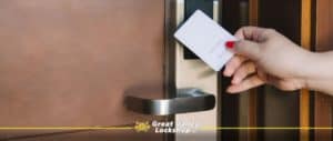 A guest holds a hotel key card near a proximity reader on the door.