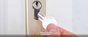 Homeowner holds a broken key in front of a door lock.