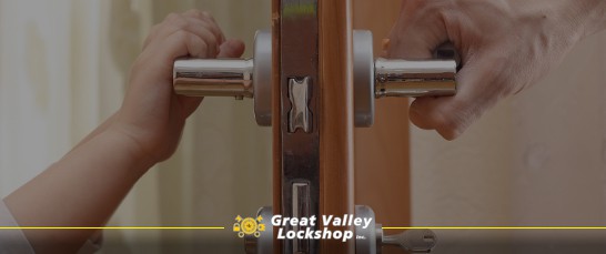 Two people hold opposite handles of a door lock.