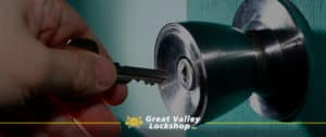 A hand holds a key up to a double cylinder lock.
