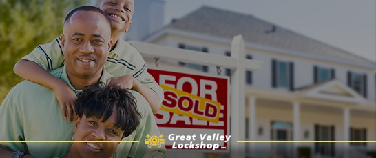 A happy family stands in front of the For Sale sign of a new house.